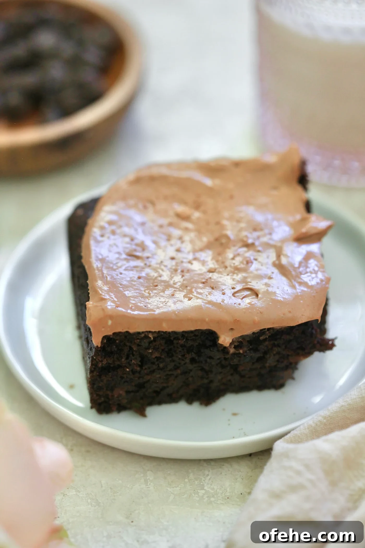 Decadent Chocolate Zucchini Cake That Actually Nourishes 8 frosted cake on plate.