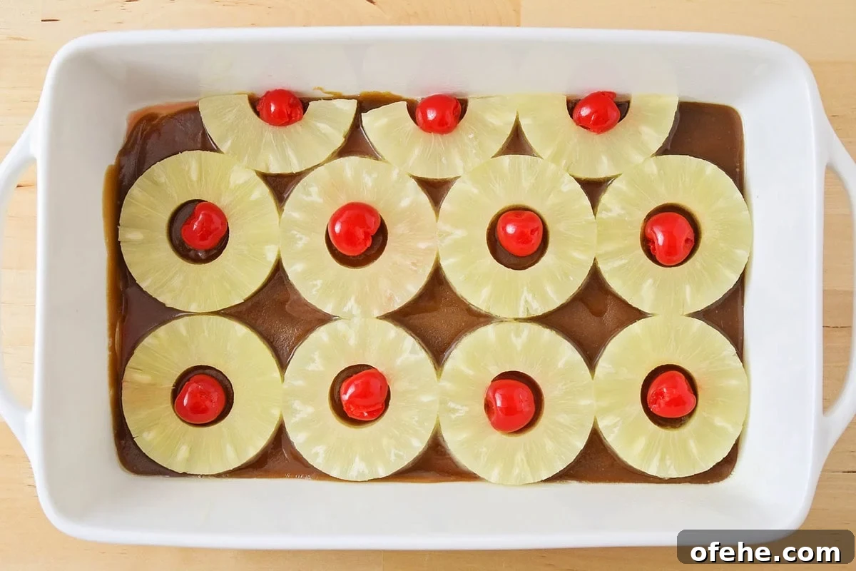 Our best pineapple upside down cake is a family favorite with a secret ingredient that takes this classic to a whole new level! Pineapple rings, sauce, and cherries in the bottom of a baking dish.