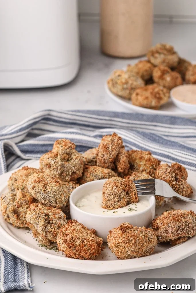 Crispy Air-Fried Mushrooms Recipe for Quick Snacks 2 Golden brown fried mushrooms on a white plate dipped in ranch dressing.