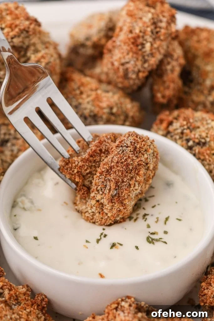 Crispy Air-Fried Mushrooms Recipe for Quick Snacks 3 Golden brown mushroom being dipped in ranch dressing on a fork