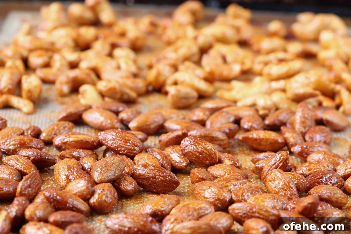 Maple Sriracha Roasted Nuts Recipe — Sweet-Spicy Snack Guide 4 roasted almonds and cashews on a sheet pan.
