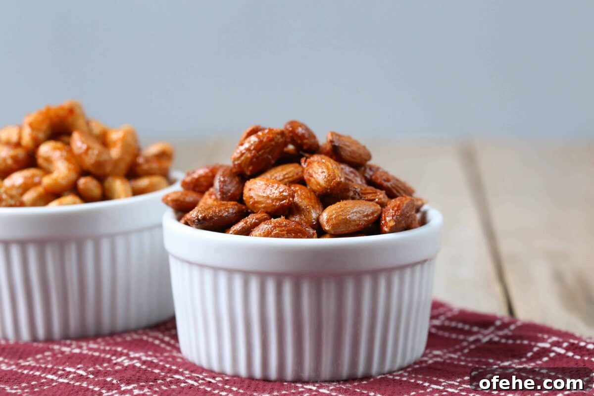 Maple Sriracha Roasted Nuts Recipe — Sweet-Spicy Snack Guide 5 roasted almonds in a white bowl on a burgundy tea towel.