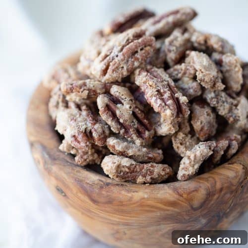 cinnamon roasted pecans in a wooden bowl on a white table.