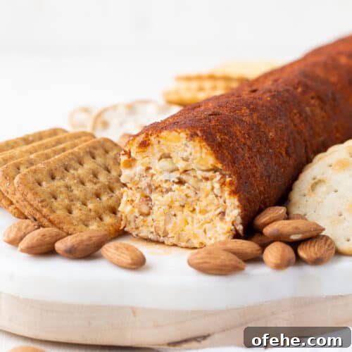 cheese roll on a marble board with crackers and almonds.
