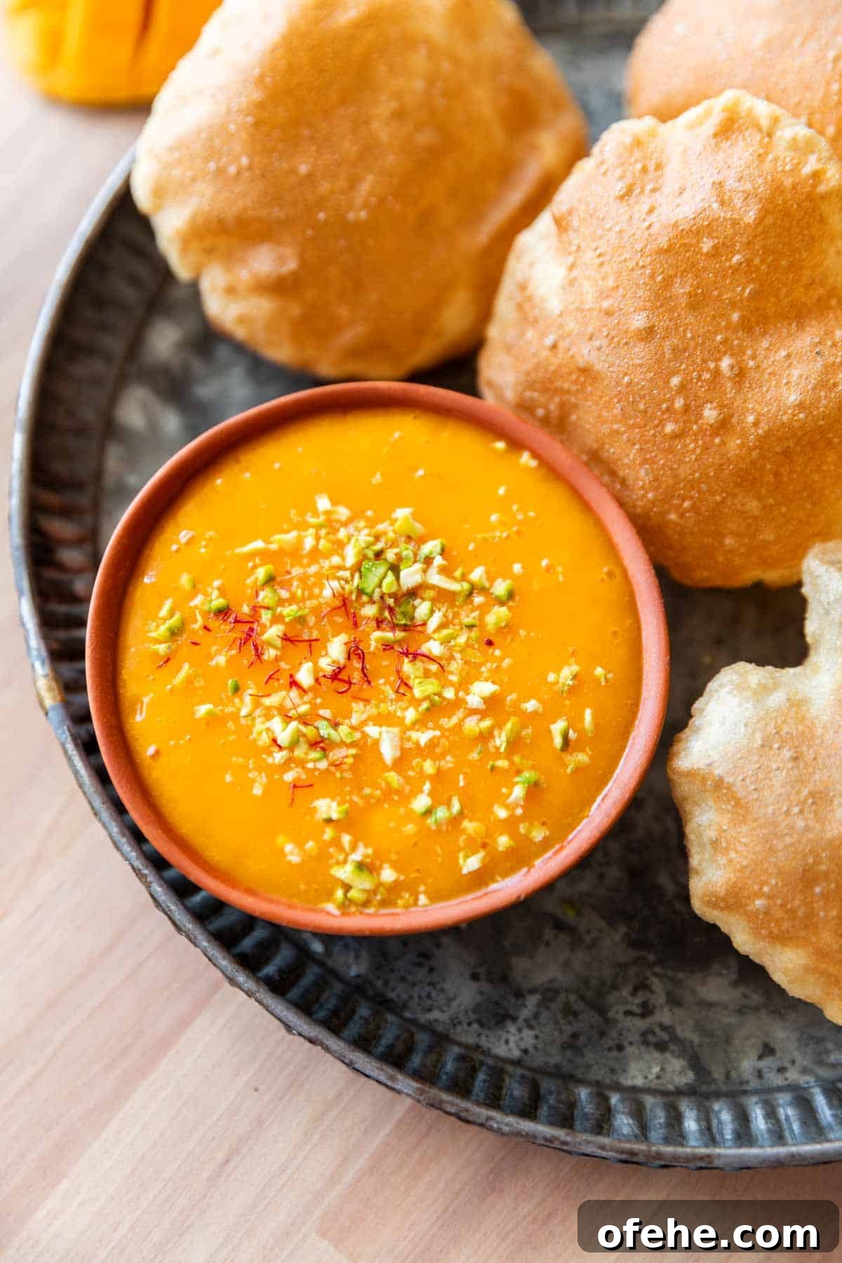 Authentic Aam Ras Recipe: Creamy Mango Pulp for Indian Meals 2 picture of aam ras on a plate with many puris