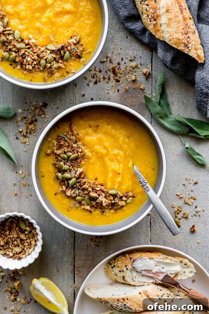 Golden Beet, Carrot & Ginger Soup — Vegan Recipe Guide 6 Overhead view of two bowls of golden beet soup with granola sprinkled on top and bread off to the side.