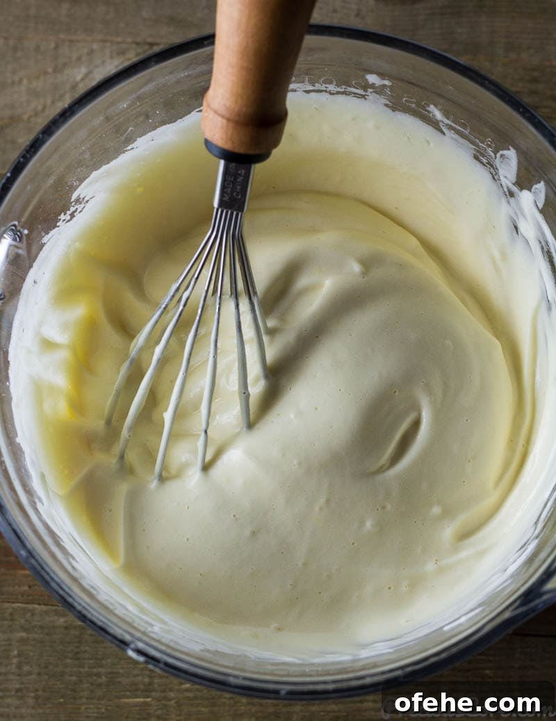 Classic Vanilla Sponge Cake Recipe for Light, Fluffy Layers 5 Whisk in a bowl with egg whites, vanilla, and egg yolks.