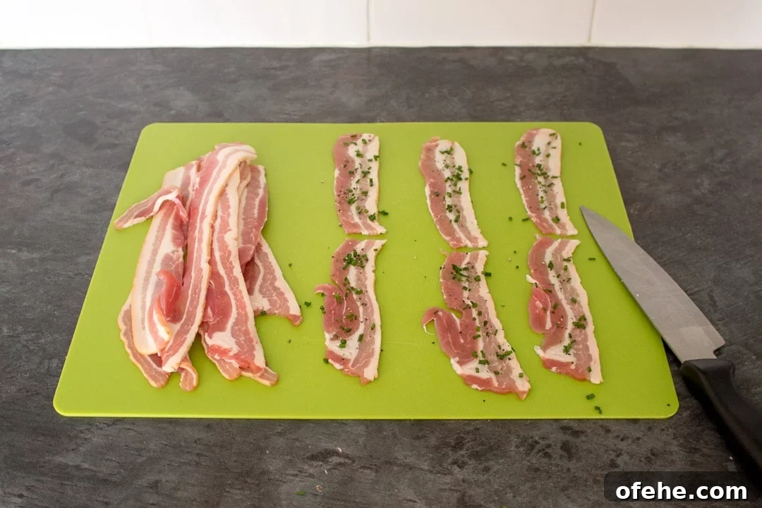 Crispy Bacon-Wrapped Halloumi Bites Recipe 11 Bacon rashers on a chopping board with chives.