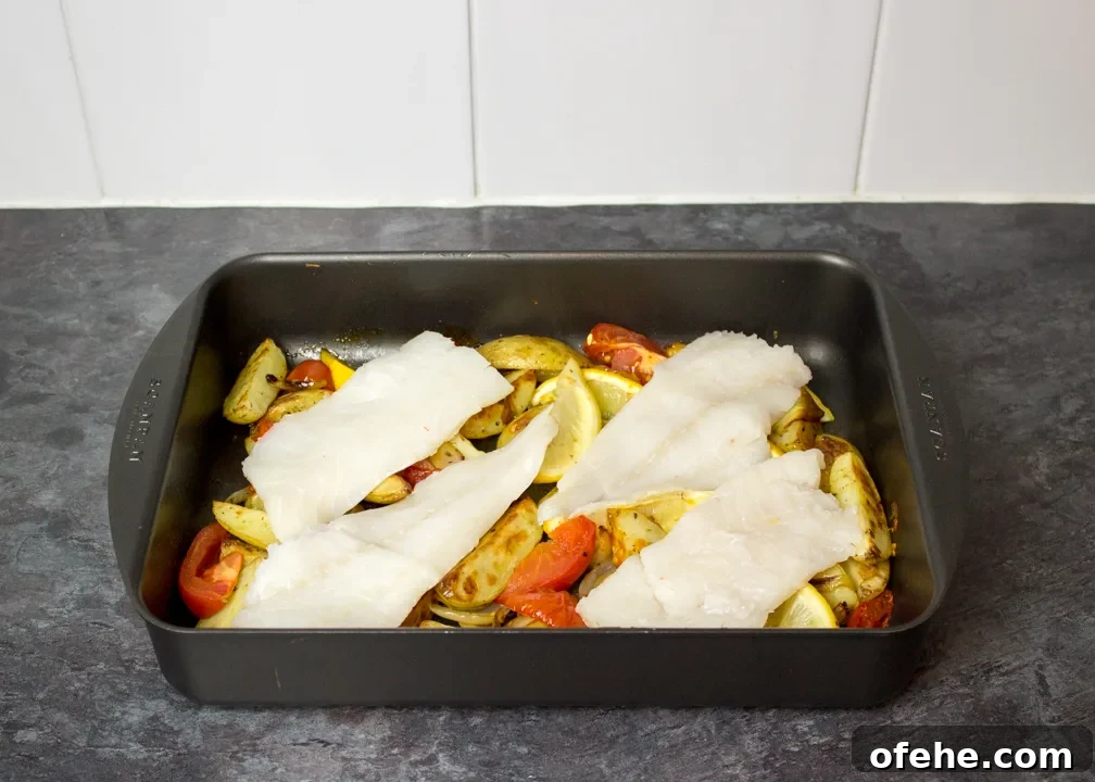 Crispy Oven-Baked Fish and Chips with Lemon Herb Tartar 5 Partially cooked potato wedges and raw fish in a roasting pan