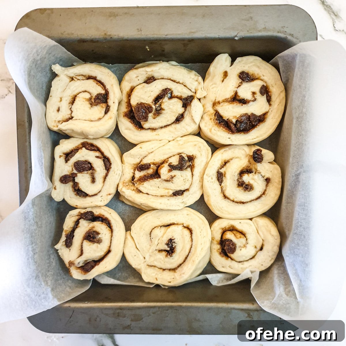 Homemade Chelsea Buns: Soft Cinnamon-Spiced Sticky Buns 16 Unbaked buns arranged in a lined baking pan.