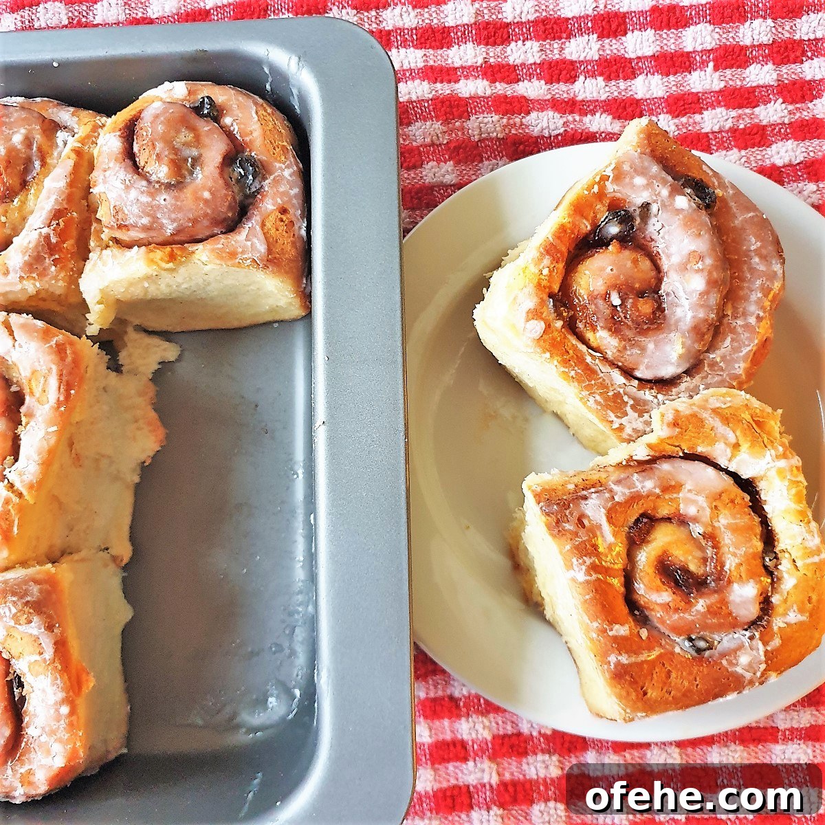 Homemade Chelsea Buns: Soft Cinnamon-Spiced Sticky Buns 21 Two chelsea buns on a white plate on a red and white checked cloth.
