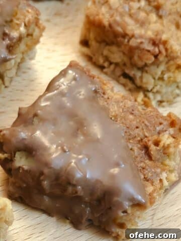 Close up of a chocolate-coated condensed milk flapjack on a wooden board.