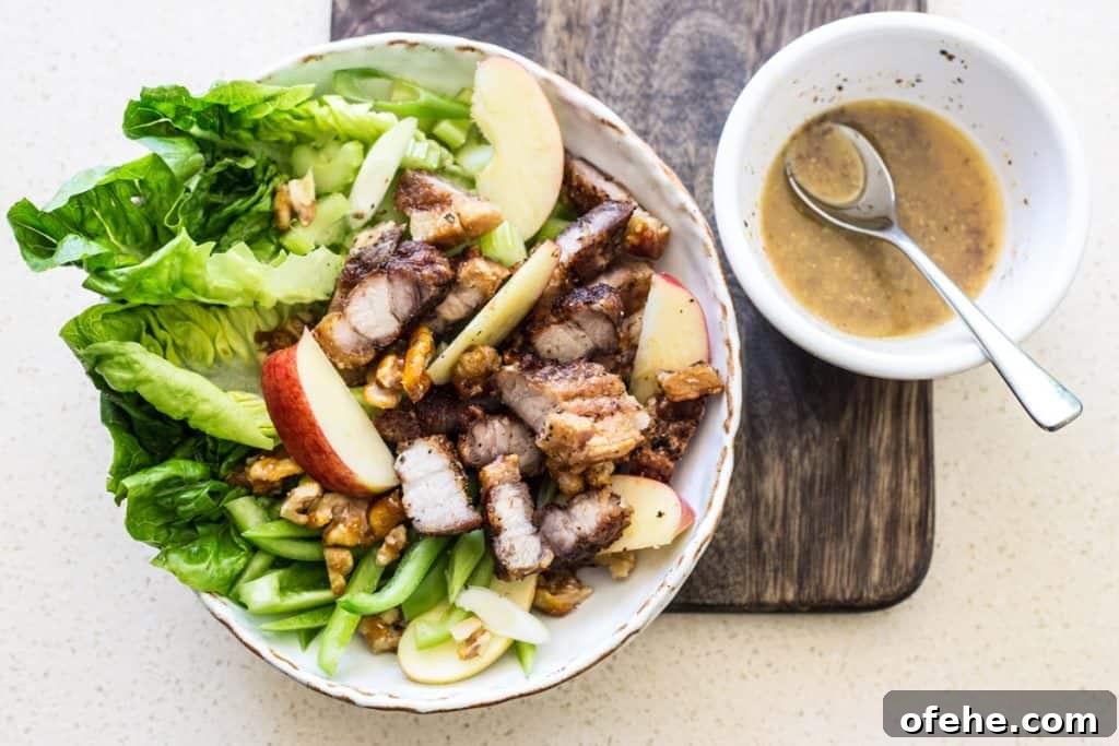 Bowl of Roast Pork Belly Apple & Caramelised Walnut Salad on a wooden board