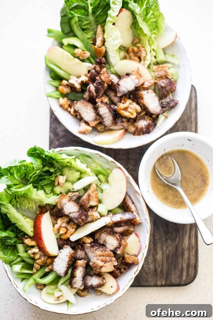 Bowls of Roast Pork Belly Apple & Caramelised Walnut Salad on a wooden board