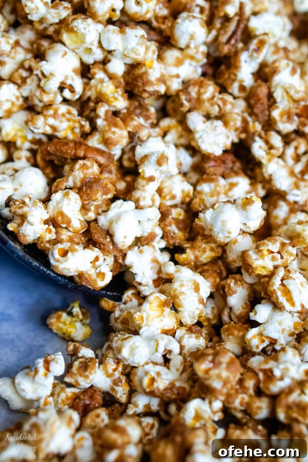 Salted Caramel Pecan Popcorn Recipe — Sweet & Crunchy Snack 3 A close up image of the popcorn that shows the texture of the caramel on the popcorn and pecans.