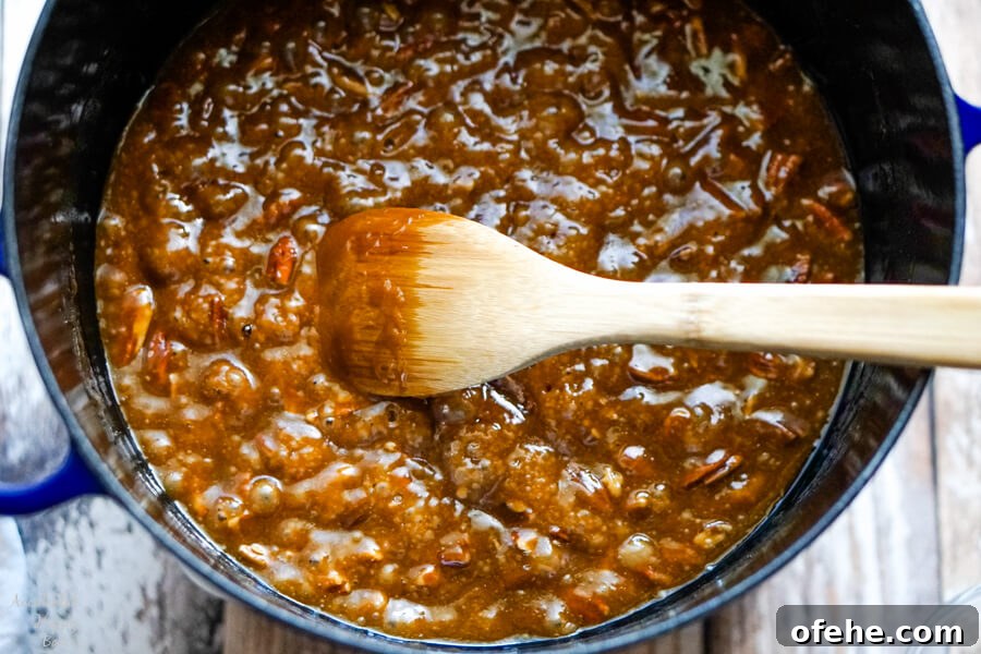Salted Caramel Pecan Popcorn Recipe — Sweet & Crunchy Snack 5 A dutch oven filled with caramel that is boiling.