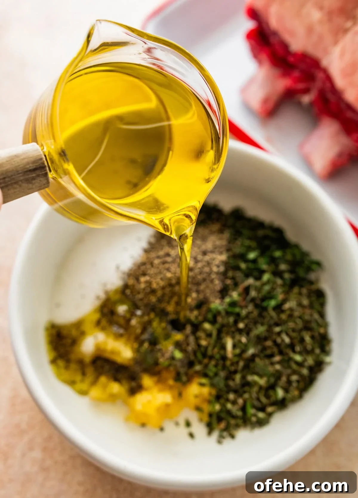 Garlic Herb Crusted Prime Rib Rub: Savory Seasoning Blend 7 pouring olive oil into bowl with herbs for the meat marinade.