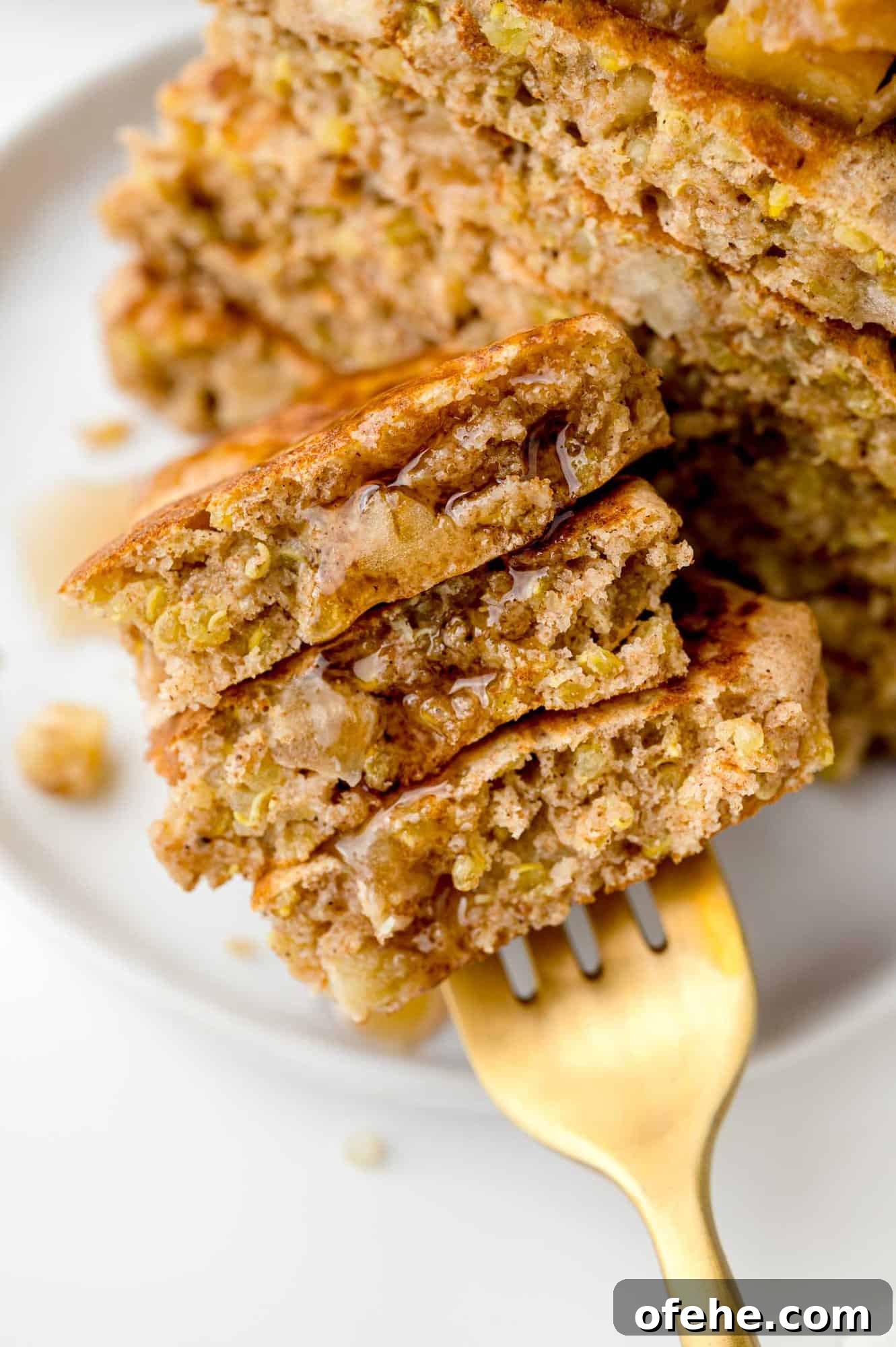 Apple Quinoa Pancakes That Crisp Up Perfectly 2 Apple quinoa pancakes on a fork with syrup.