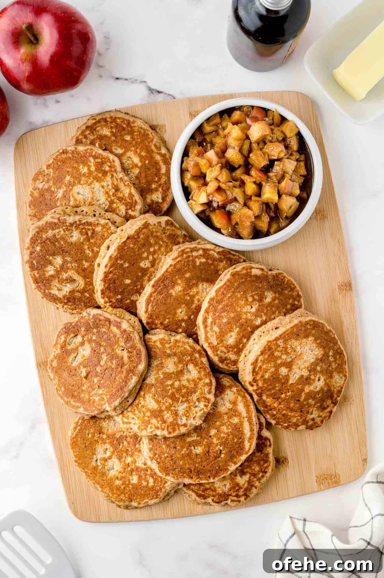 Apple Quinoa Pancakes That Crisp Up Perfectly 3 Apple quinoa pancakes on a wooden cutting board.