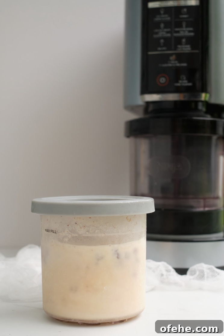 Oreo Milkshake Recipe: How to Make It with a Ninja Creami 4 the oreo milkshake in a pint container sitting in front of the Ninja Creami machine