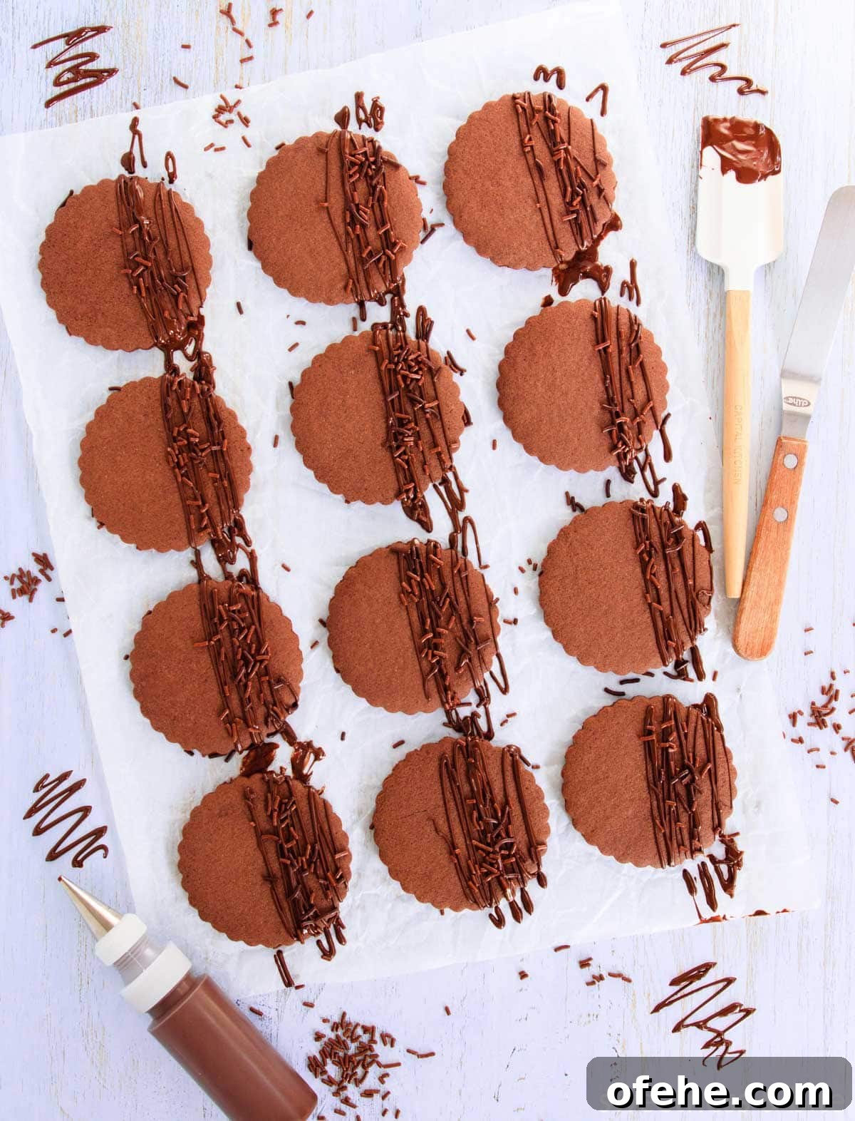 Chocolate cookies, drizzled with melted dark chocolate, with chocolate sprinkles, on a blue woodgrain background.