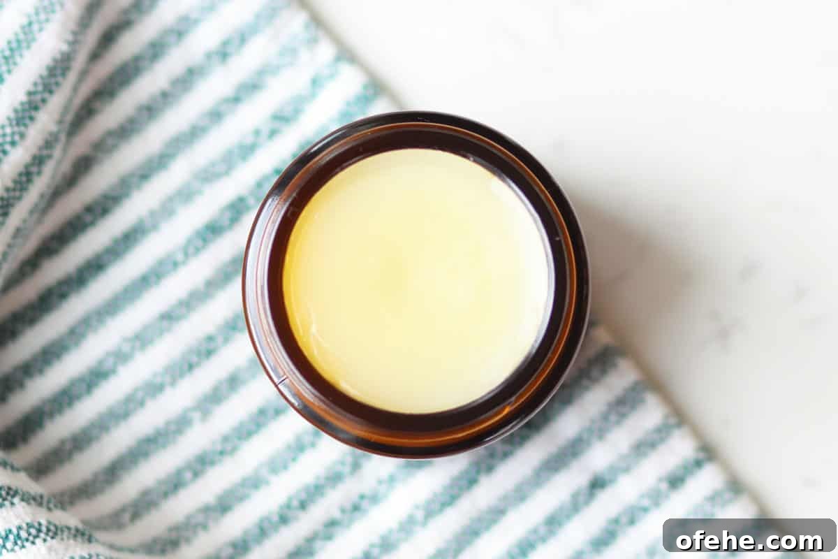 DIY Natural Vapor Rub with Essential Oils for Congestion Relief 3 an amber glass jar with homemade vapor rub in it with a striped green and white towel laid under it