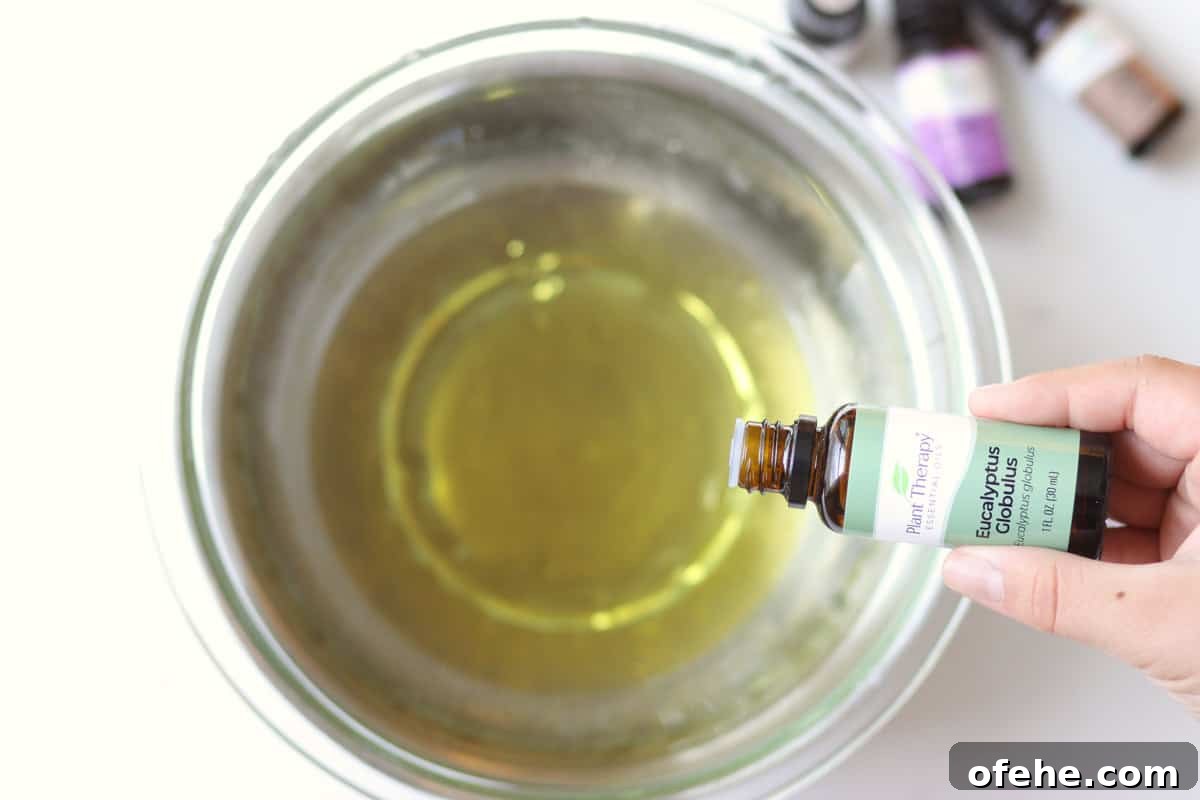 DIY Natural Vapor Rub with Essential Oils for Congestion Relief 5 eucalyptus oil being dripped into a bowl with melted vapor rub in it