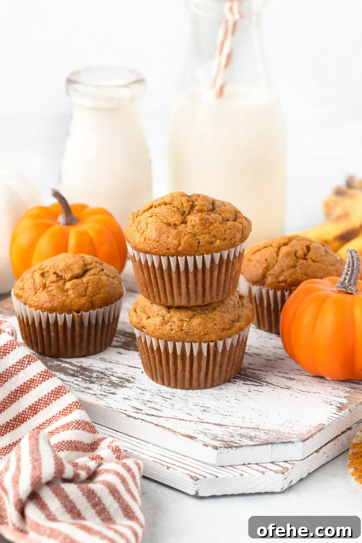 Banana Pumpkin Muffins with Warm Spices — Moist Fall Recipe 2 Pumpkin and Banana Muffins stacked on a white board.