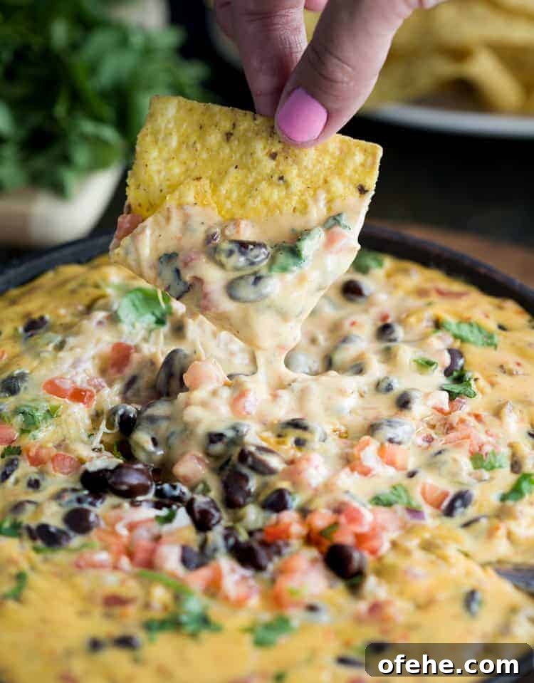 tortilla chip dipping into cheese dip.