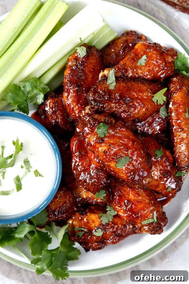 chicken wings smothered in sauce with ranch on the side.