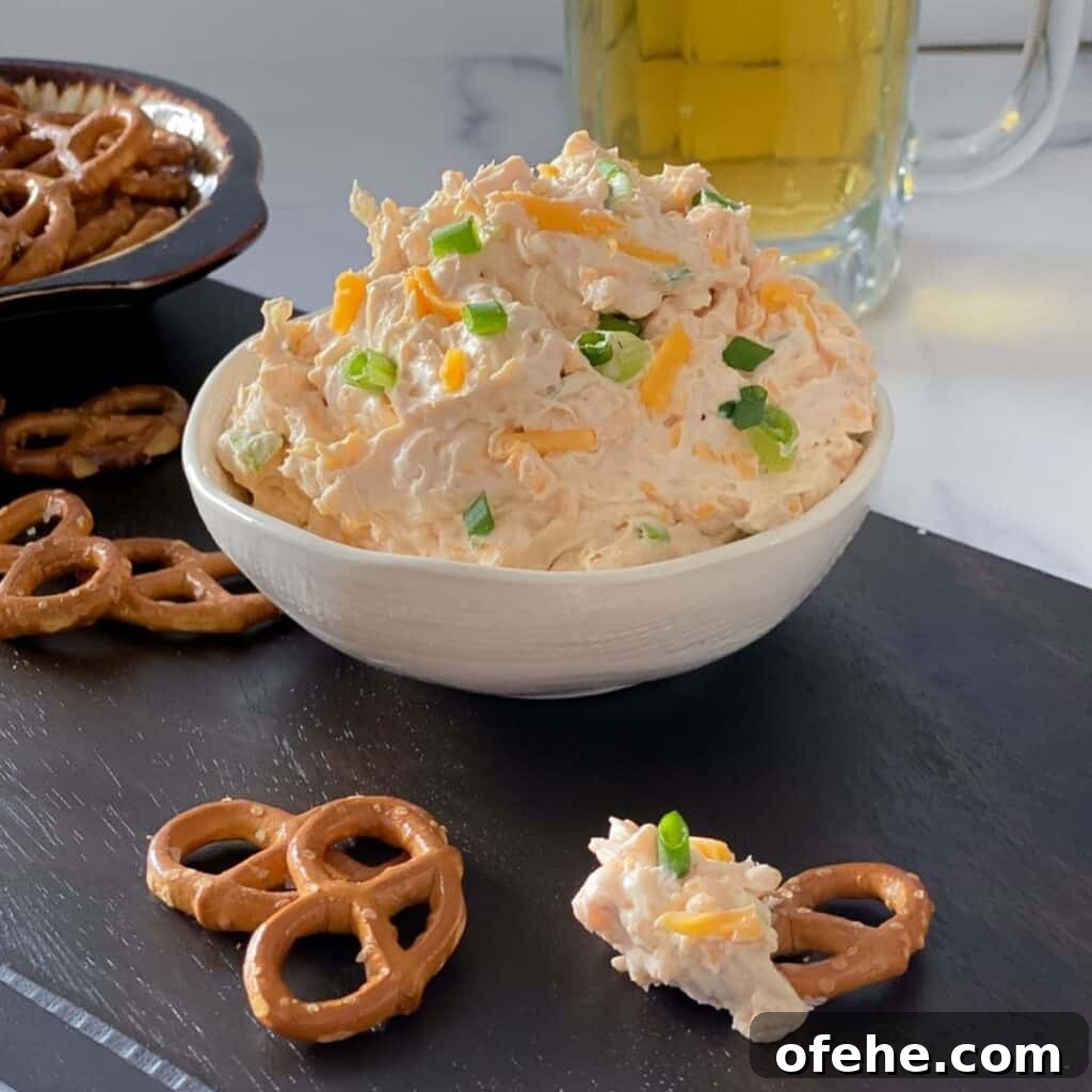 beer cheddar cheese dip with pretzels on a cutting board.