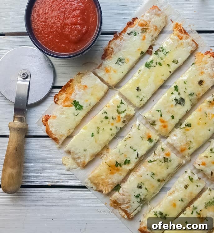 cheesy bread on a table cut into sticks with marinara on the side.