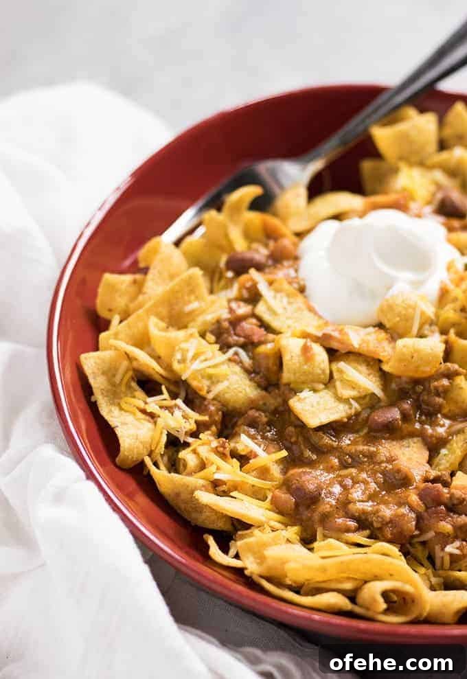 corn chips topped with chili and sour cream in a bowl.