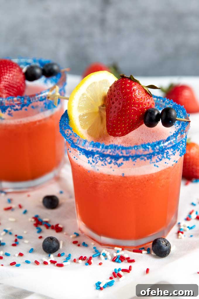 Two glasses with blue sugar on the rim and filled with Lemonade vodka cocktail
