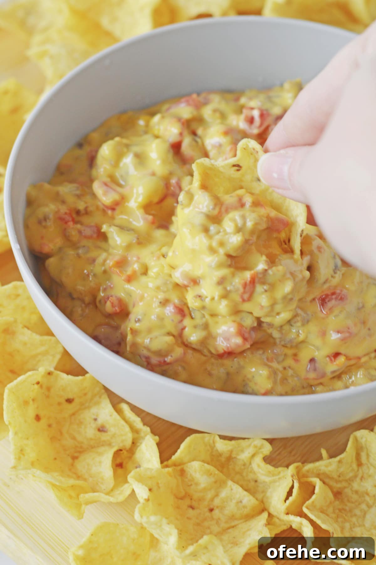 Creamy Queso Dip with Rotel Tomatoes and Diced Chilies 2 tortilla chip being dipped into a bowl of cheese dip.