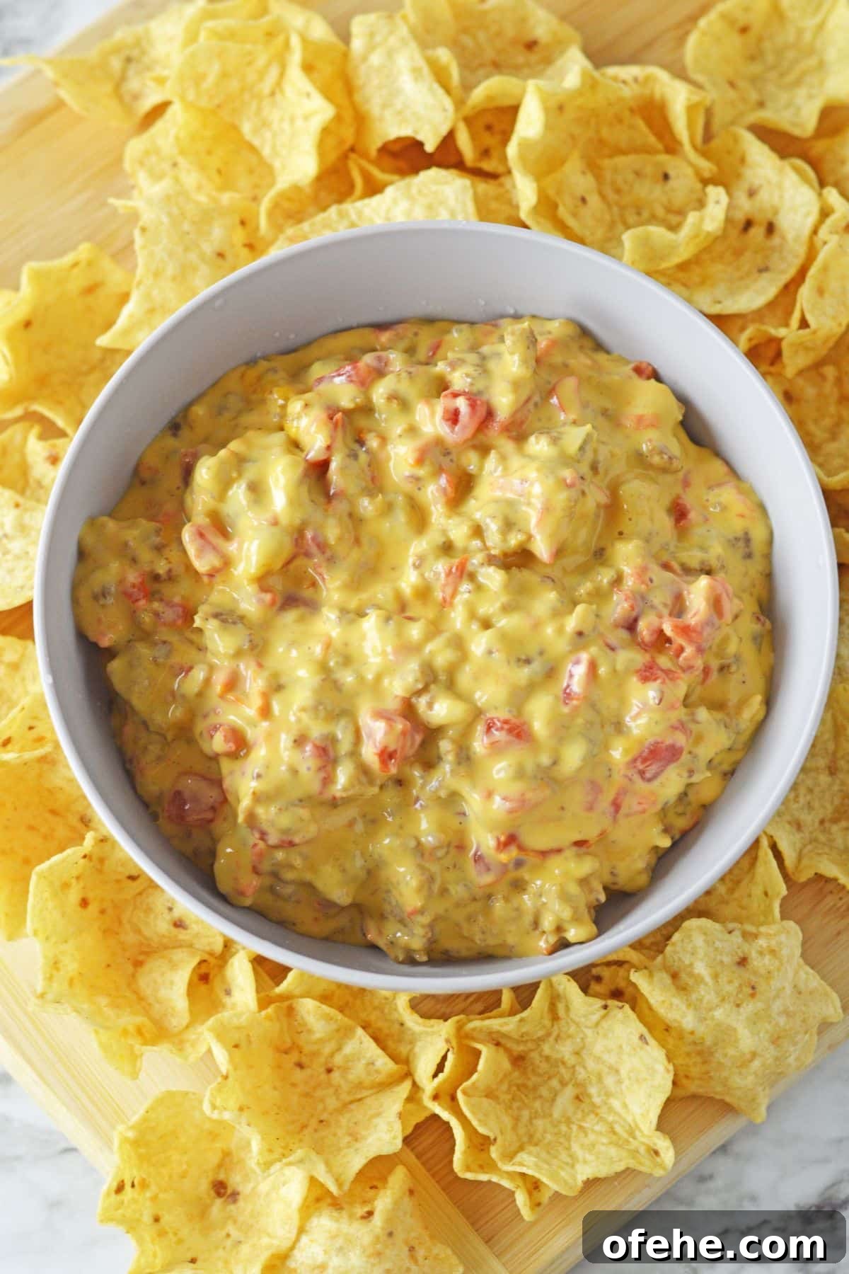 Creamy Queso Dip with Rotel Tomatoes and Diced Chilies 3 bowl full of cheese and rotel dip surrounded by tortilla chips.
