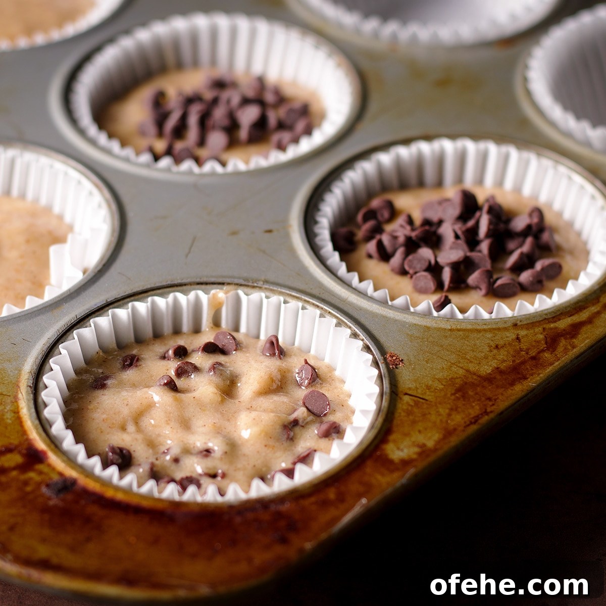 Sprinkling mini chocolate chips over muffin batter to make gluten free chocolate chip banana muffins.