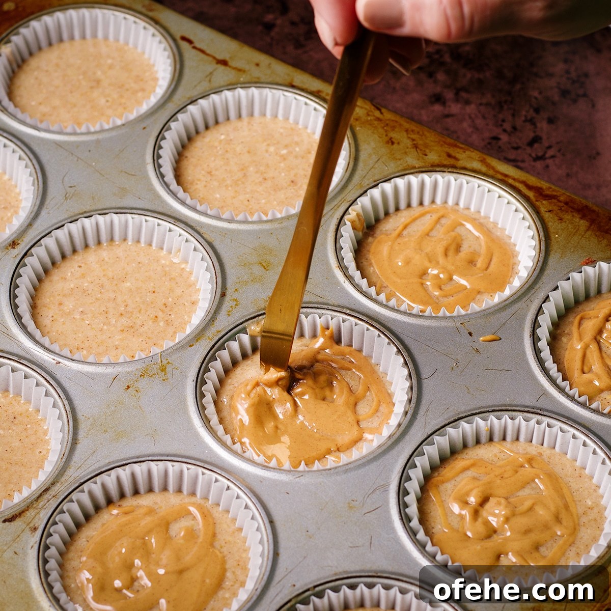 Using a butter knife to swirl peanut butter into gluten free banana muffin batter before baking.