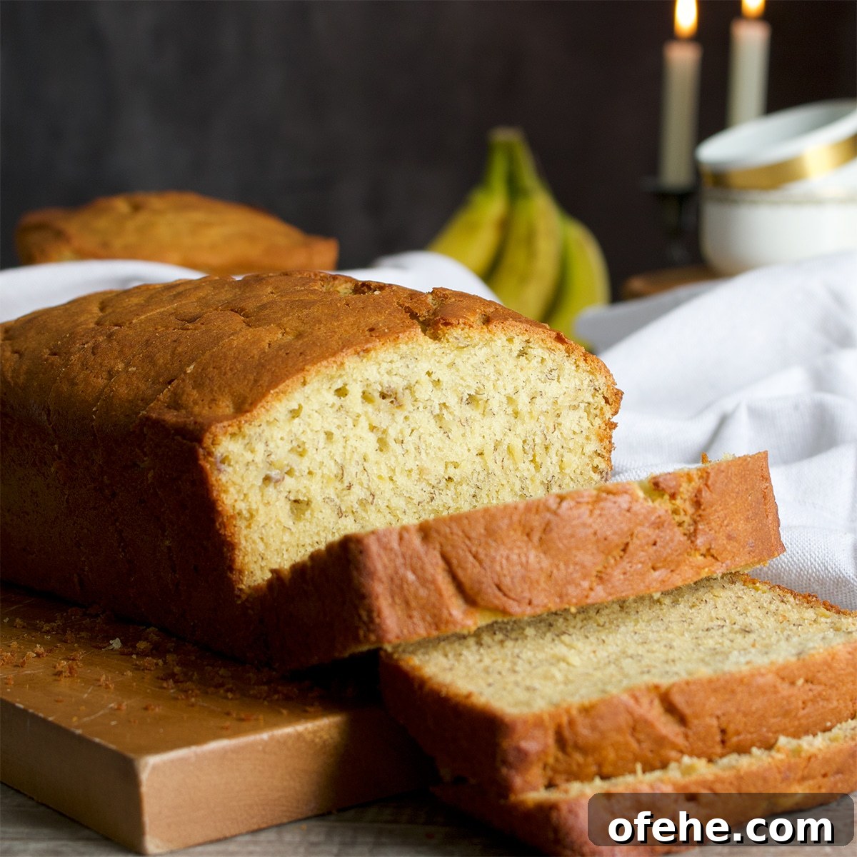 A loaf of homemade banana bread on a cutting board with slices fanning down so you can see the inside of the loaf.