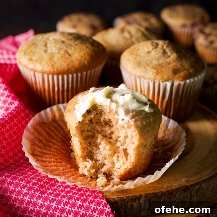 A jumbo gluten free banana muffin slathered with butter with a bite taken out of it.
