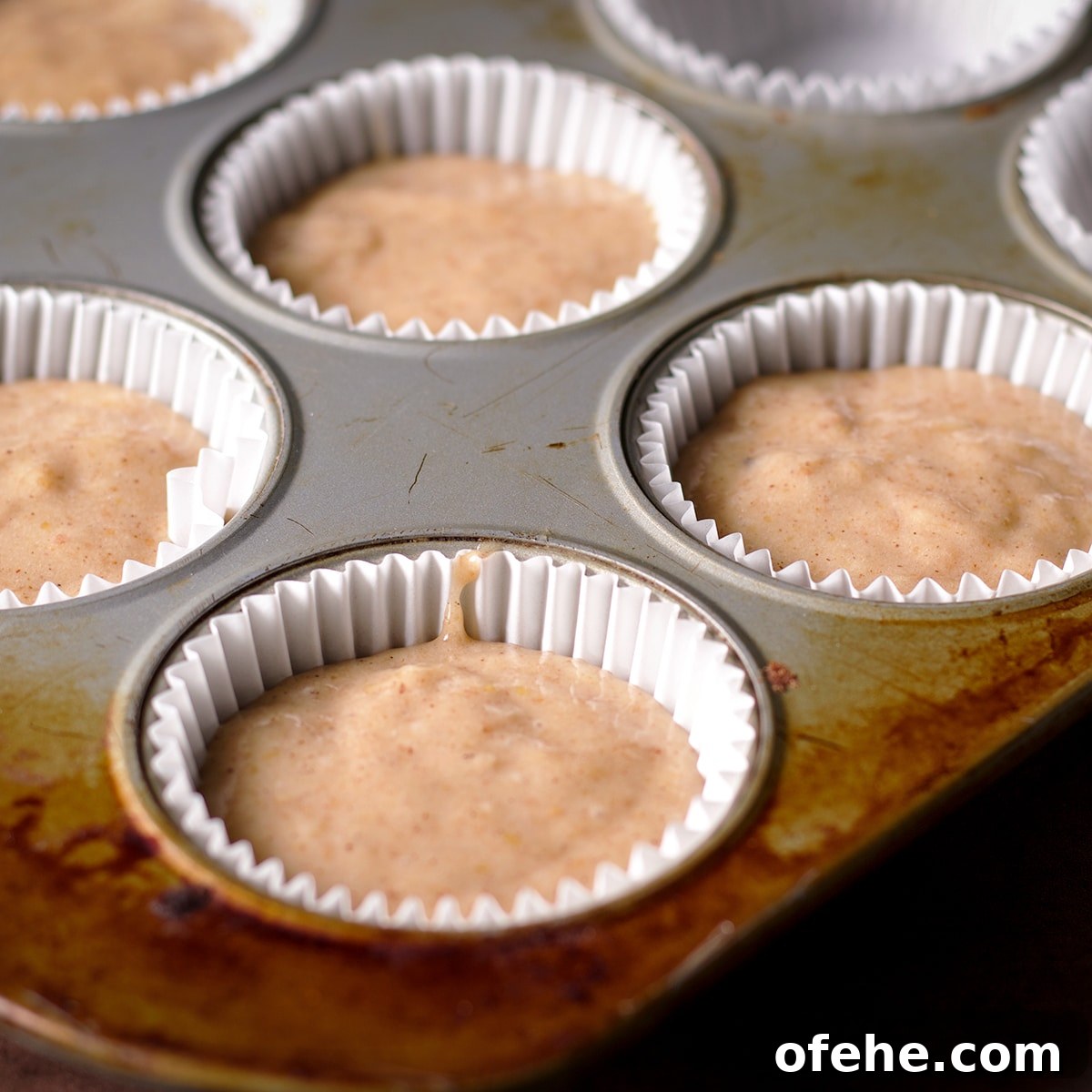 A muffin pan filled with raw muffin batter ready to bake.