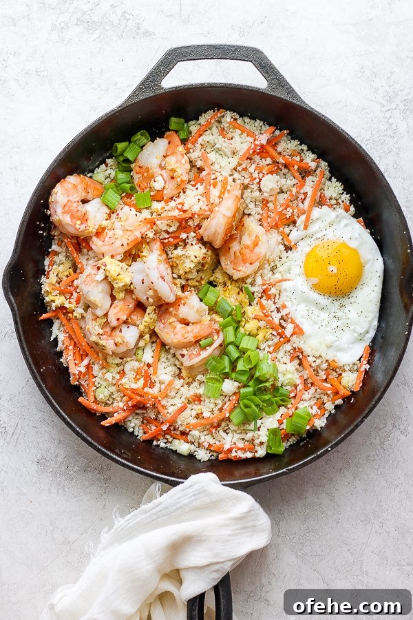 Shrimp Fried Cauliflower Rice - for when you are craving take-out, but also want to eat clean! (Paleo + Whole30 + Gluten-Free) #whole30recipes #shrimpfriedcauliflowerrice #paleorecipes #easyweeknightdinners Shrimp fried cauliflower rice in a cast iron skillet.