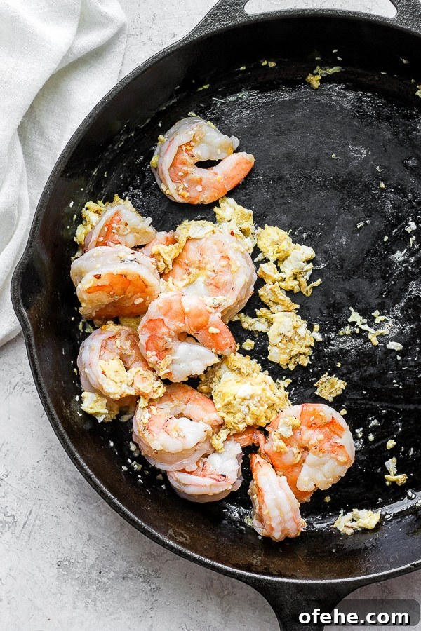 Shrimp Fried Cauliflower Rice - for when you are craving take-out, but also want to eat clean! (Paleo + Whole30 + Gluten-Free) #whole30recipes #shrimpfriedcauliflowerrice #paleorecipes #easyweeknightdinners Pan fried shrimp and egg in a cast iron skillet.