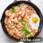 Shrimp Fried Cauliflower Rice Recipe — Low-Carb Weeknight Meal 3 A cast iron skillet filled with shrimp fried cauliflower rice with a fried egg on top.