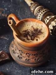 Overhead shot of Oaxacan hot chocolate in a clay mug with cinnamon stick.
