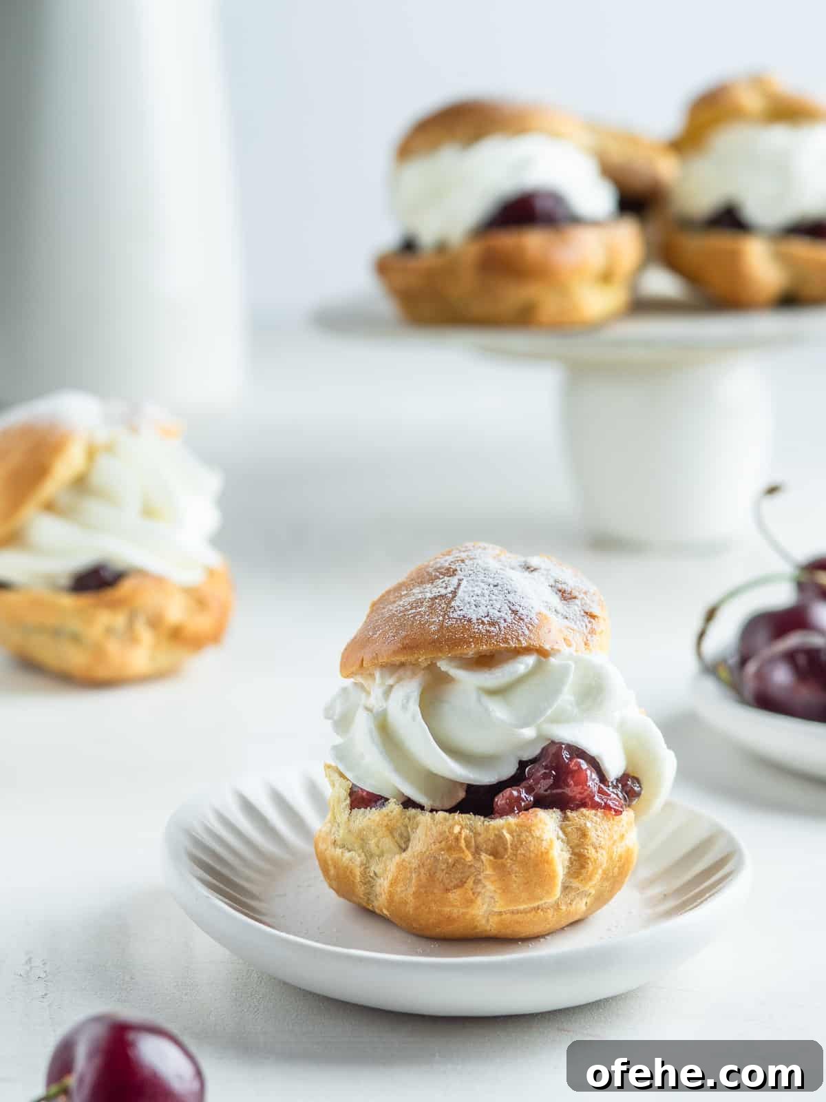 Windbeutel: Classic German Cream Puffs Recipe 3 German Windbeutel filled with cherry sauce and whipped cream on a white dessert plate