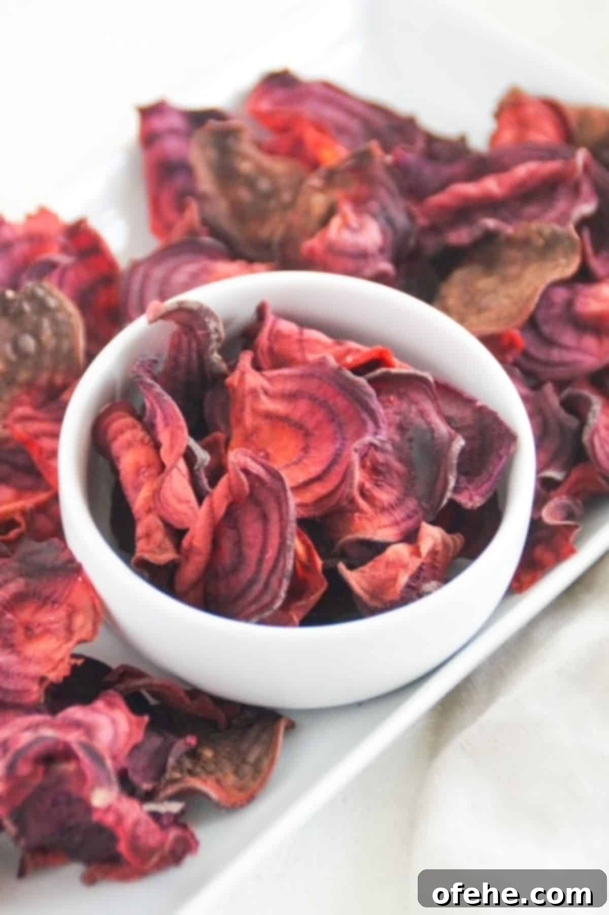 Crispy Air Fryer Beet Chips Recipe 2 Beet chips in a white bowl and white serving dish.