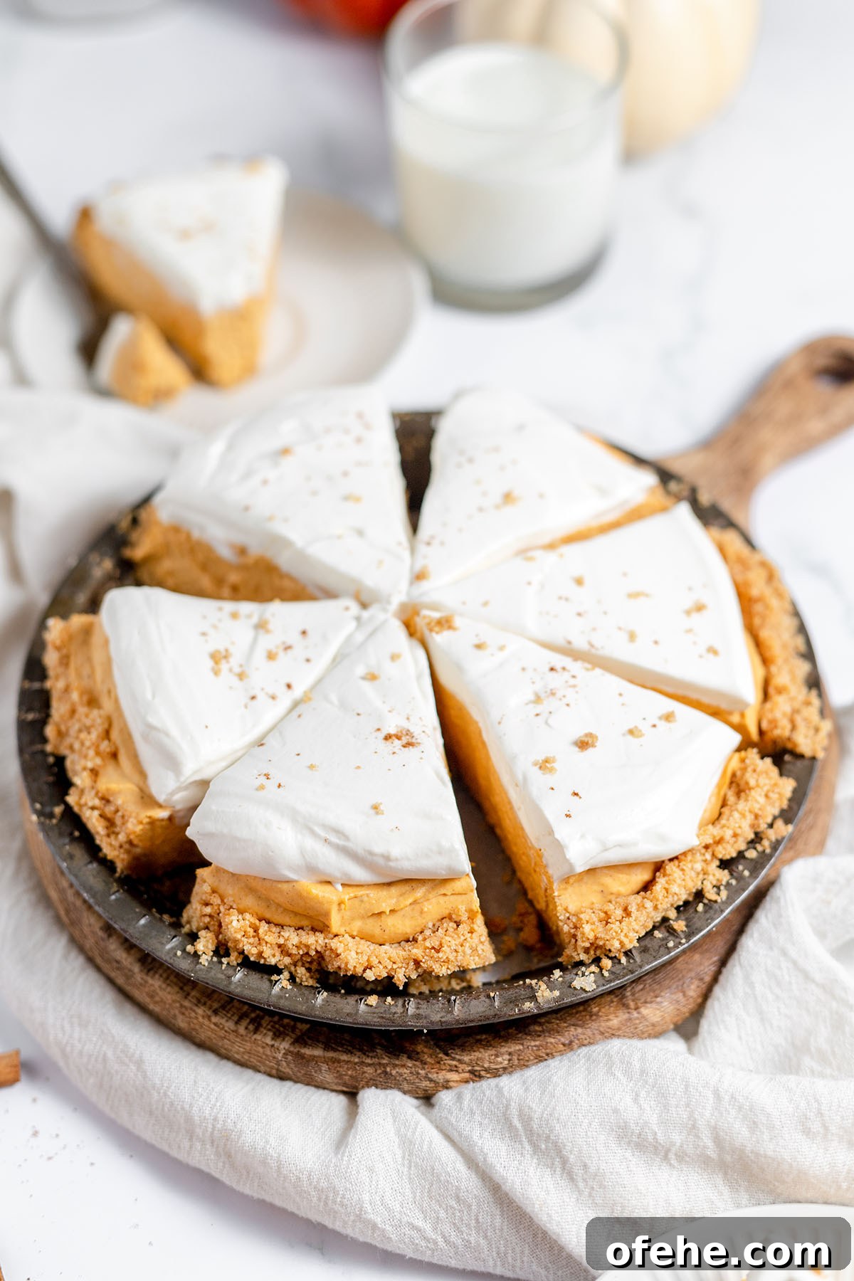Pumpkin Cheesecake sliced on a pie plate and served on a round wooden board.