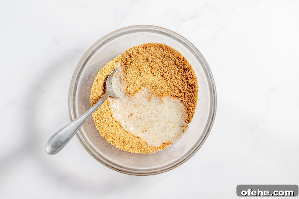 Crushed graham crackers, granulated sugar, and melted butter in a mixing bowl.