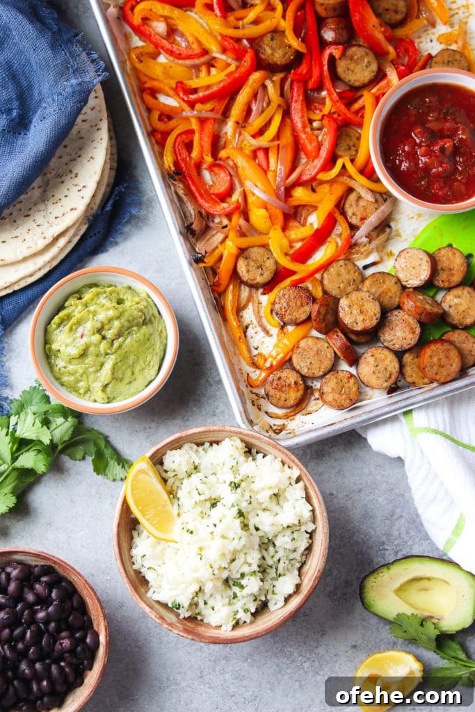 A sheet pan chicken fajitas surrounded by flat bread, a bowl of guacamole, a bowl or rice, a bowl of black beans, half a slice of avocado and some parsley